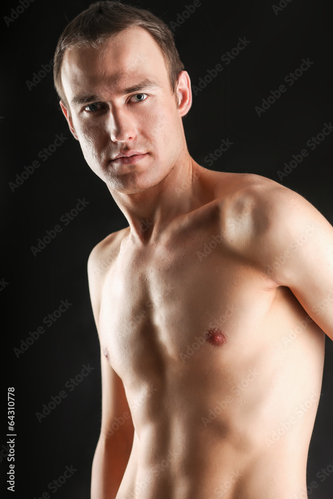 Portrait of a naked muscular man, isolated on black background