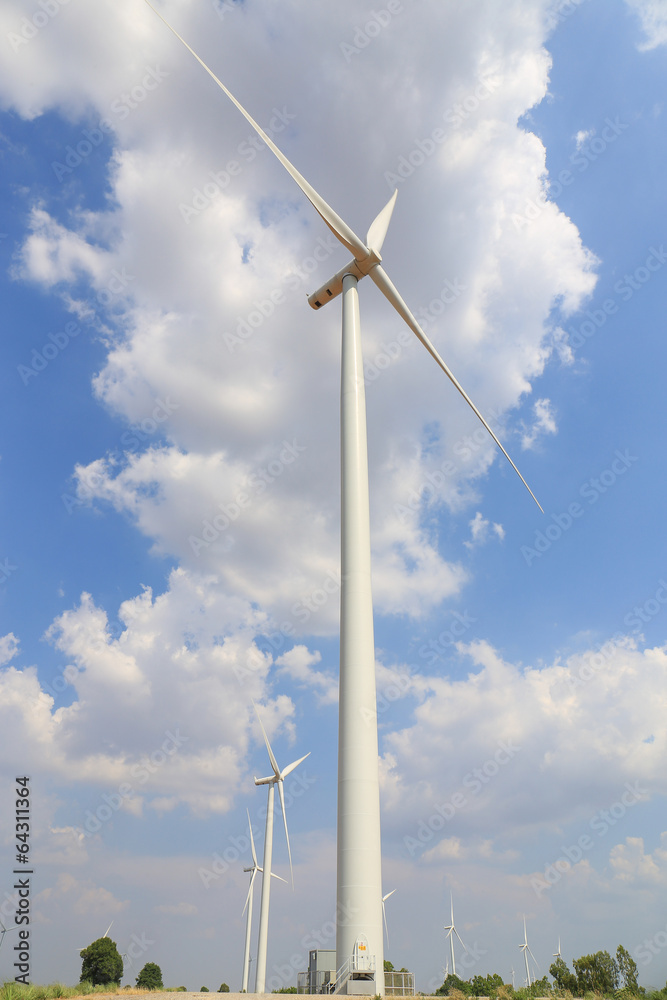 Wind turbine on the green grass over the blue clouded sky Wind turbine on the green grass over the blue clouded sky
