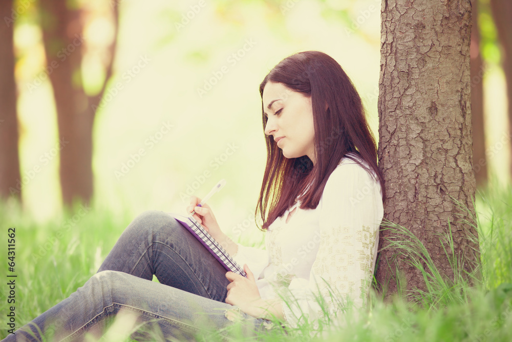Brunette girl with notebook in the park. Brunette girl with notebook in the park.