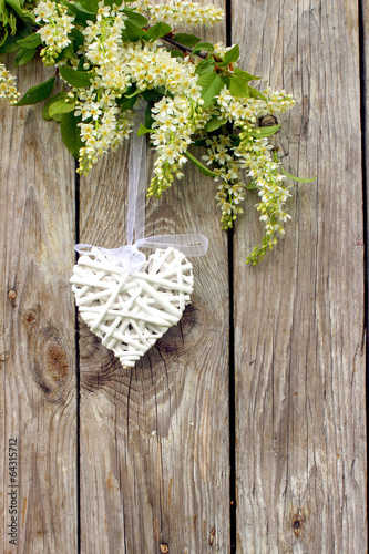 Białe serce na drewnianym tle w otoczeniu kwiatów