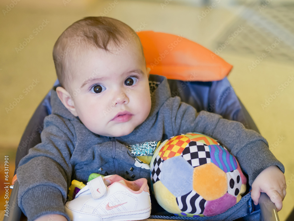 Baby girl playing with a ball of cloth on a high chair Baby girl playing with a ball of cloth on a high chair