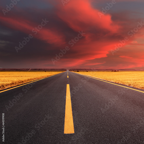 Driving on an empty asphalt road at sunset