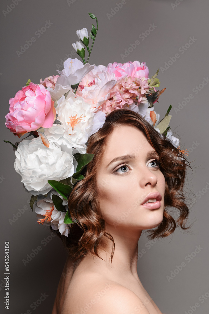 Naklejka premium Beauty portrait of a girl with flowers in her hair on a gray bac