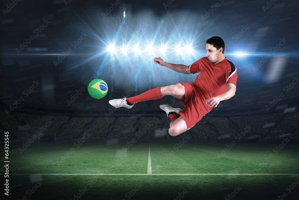 Composite image of fit football player jumping and kicking Composite image of fit football player jumping and kicking