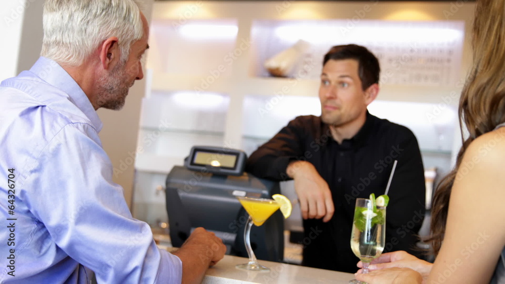 Bartender serving cocktails and chatting to customers Bartender serving cocktails and chatting to customers