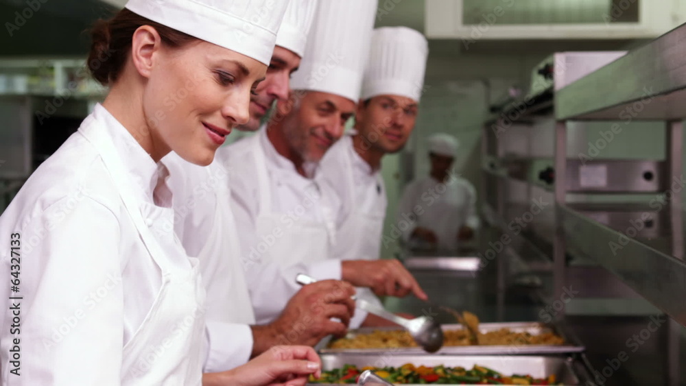Row of chefs preparing food in serving trays Row of chefs preparing food in serving trays