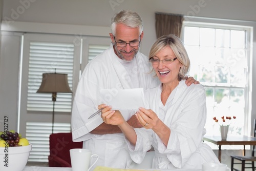 Cheerful couple looking at a document at home