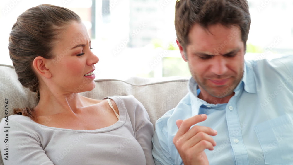 Man surprising his girlfriend with a present on the couch Man surprising his girlfriend with a present on the couch