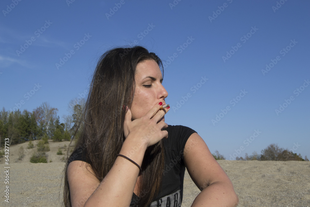 Young sexy female smoking a cigarette at the beach Young sexy female smoking a cigarette at the beach