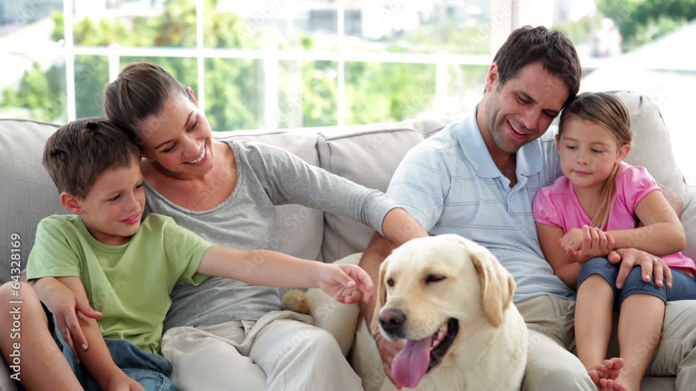 Cute family relaxing together on the couch with their labrador d Cute family relaxing together on the couch with their labrador d