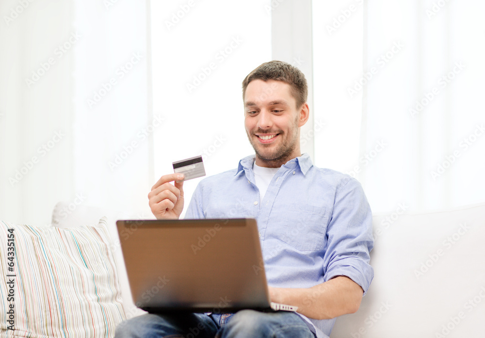 smiling man working with laptop and credit card smiling man working with laptop and credit card