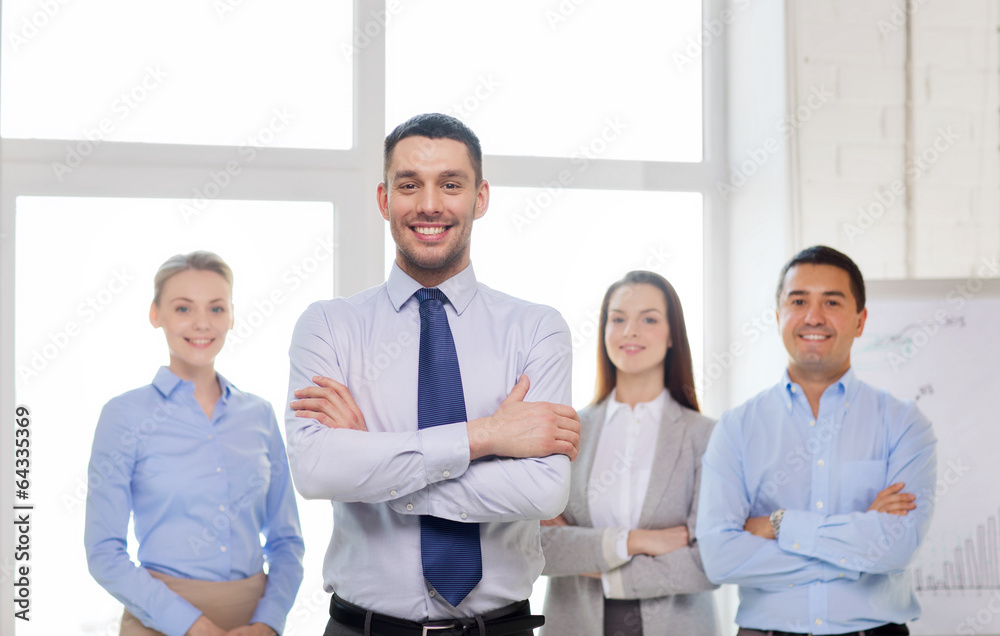 smiling businessman in office with team on back