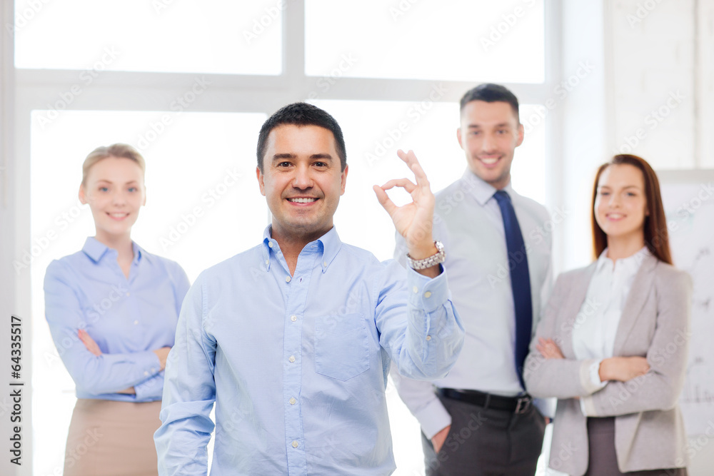 smiling businessman showing ok-sign in office