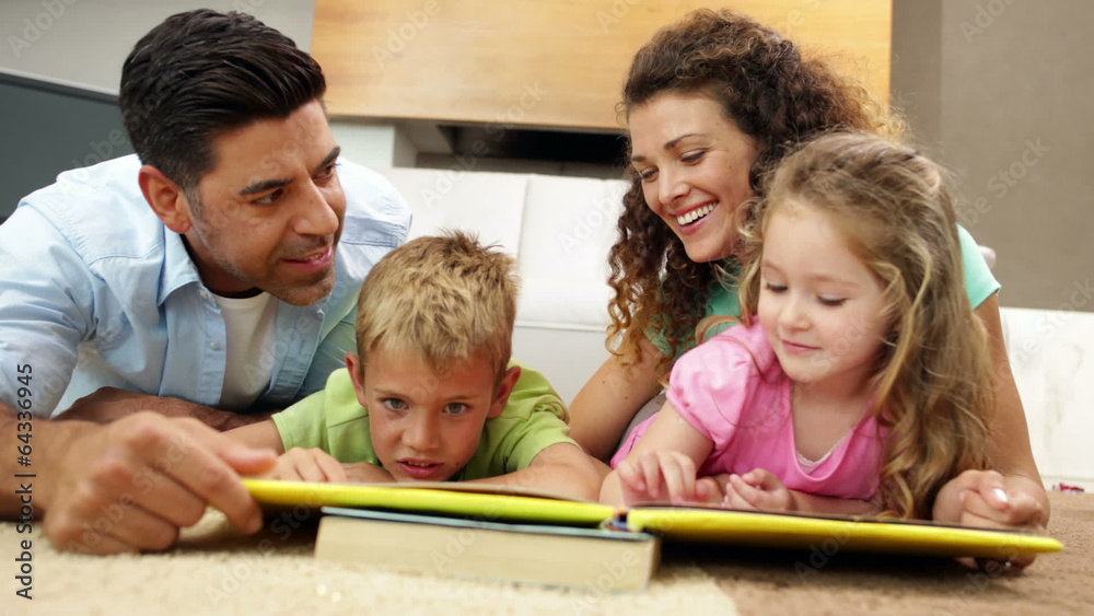 Siblings lying on floor reading book with parents Siblings lying on floor reading book with parents