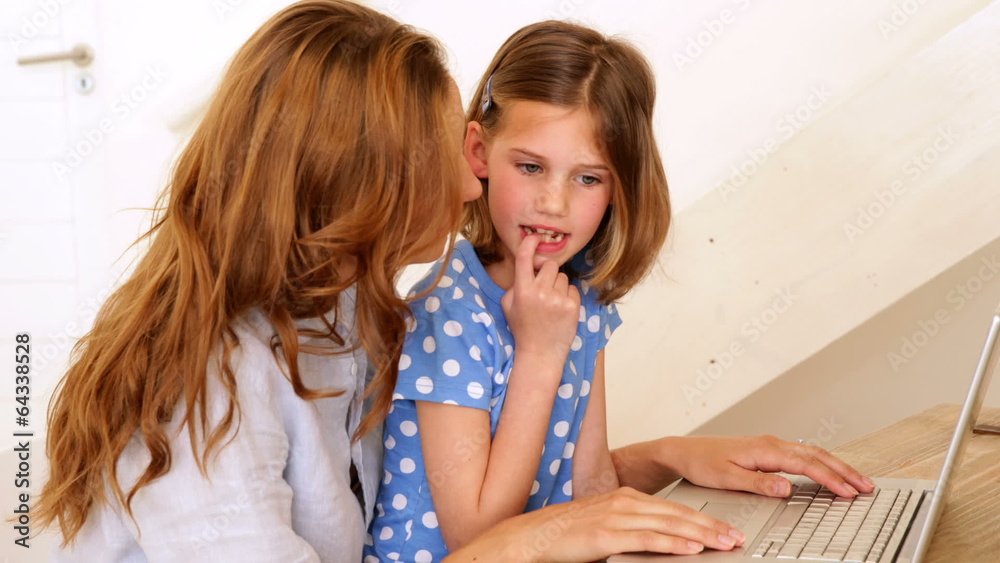 Little girl using laptop with her mother at the table Little girl using laptop with her mother at the table