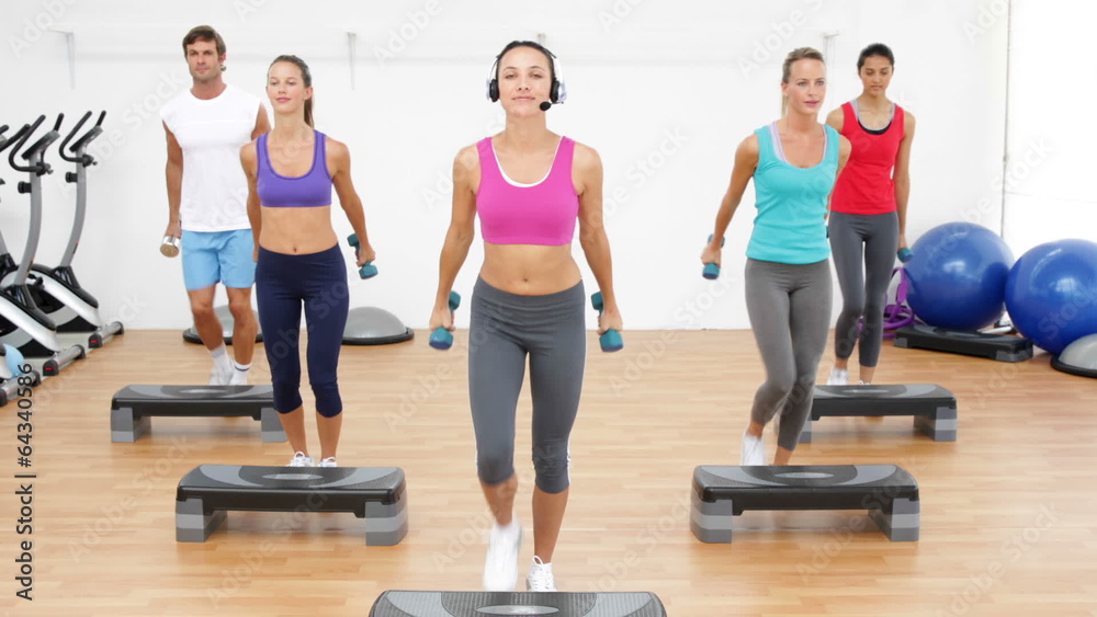 Aerobics class stepping together led by instructor and lifting d Aerobics class stepping together led by instructor and lifting d