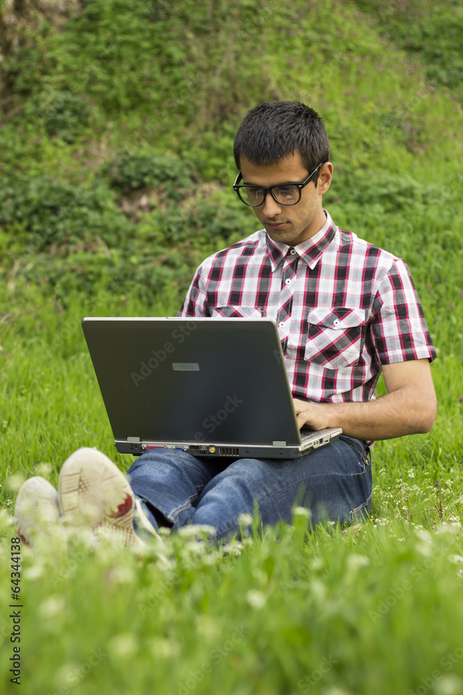 Student using a laptop on the grass Student using a laptop on the grass