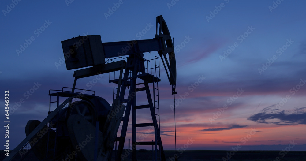Operating oil and gas well profiled on sunset sky Operating oil and gas well profiled on sunset sky