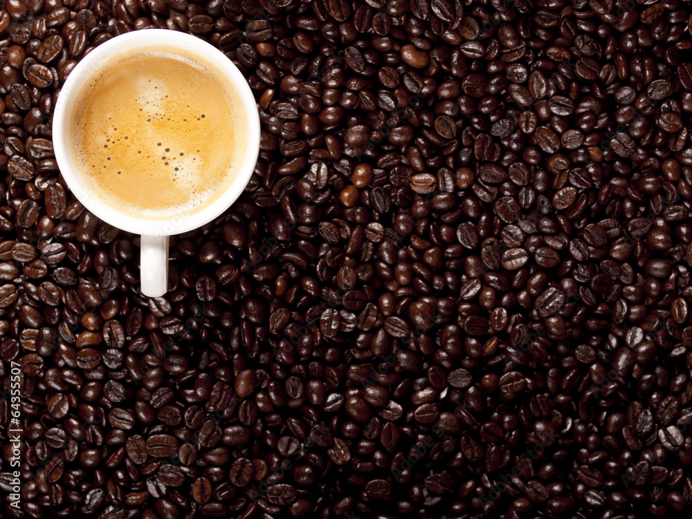Top view of a cup of dark roasted coffee with coffeebeans Top view of a cup of dark roasted coffee with coffeebeans