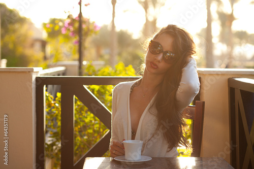Cute young brunette resting with cup of coffee