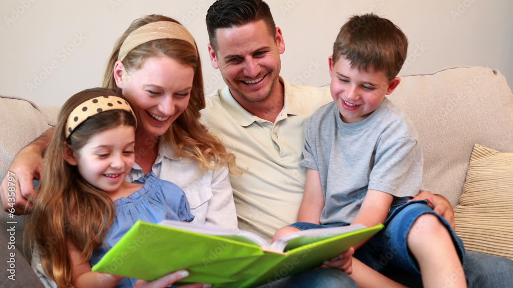 Happy young family sitting on sofa looking at photo album Happy young family sitting on sofa looking at photo album