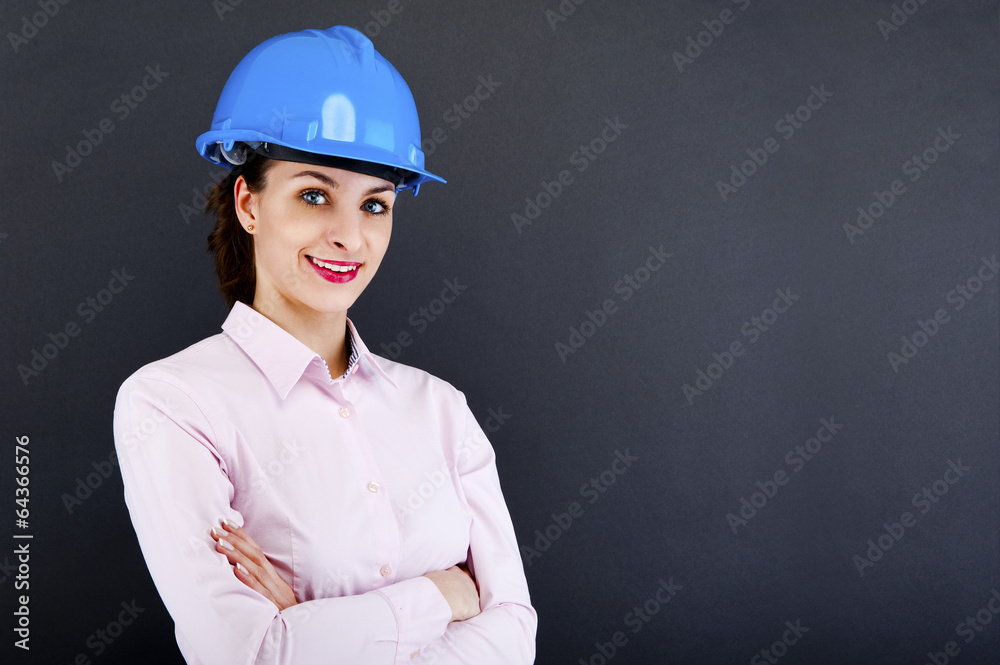 Woman architect, contractor in blue helmet over dark background Woman architect, contractor in blue helmet over dark background