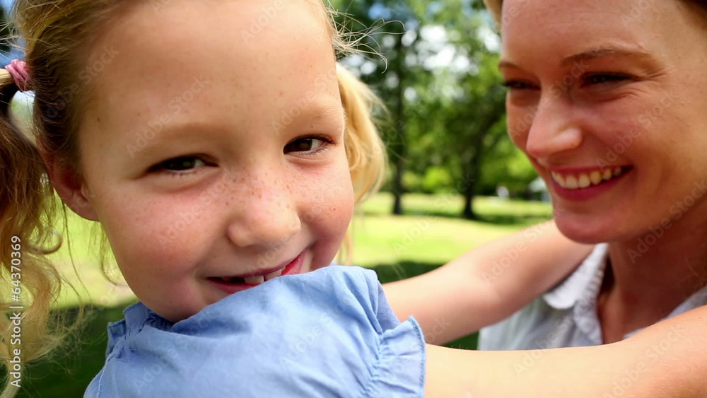 Happy mother kissing her little girl in the park Happy mother kissing her little girl in the park