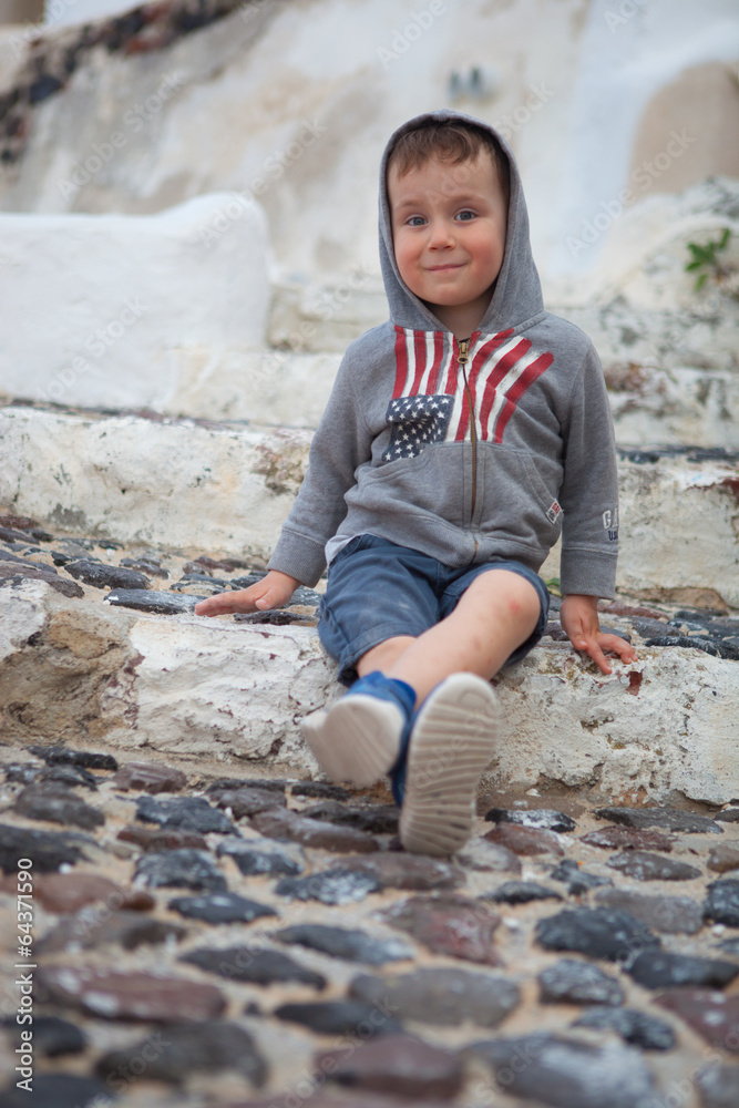 Boy is sitting on narrow street in Santorini Boy is sitting on narrow street in Santorini