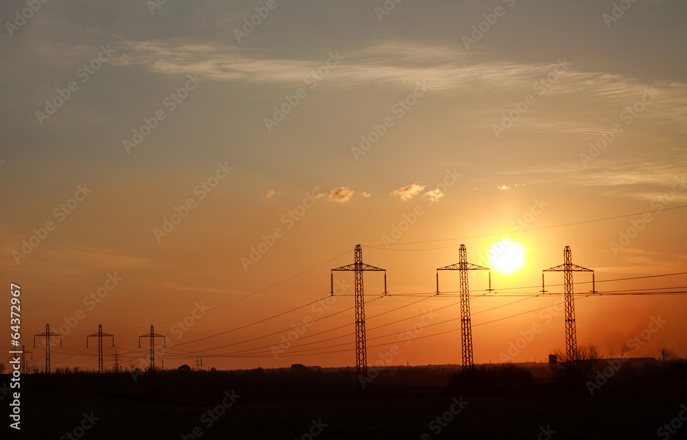 High electricity power line towers at dramatic sunset background