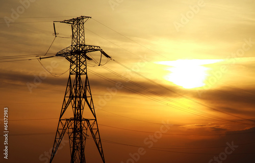 High power electric line towers at dramatic sunset background