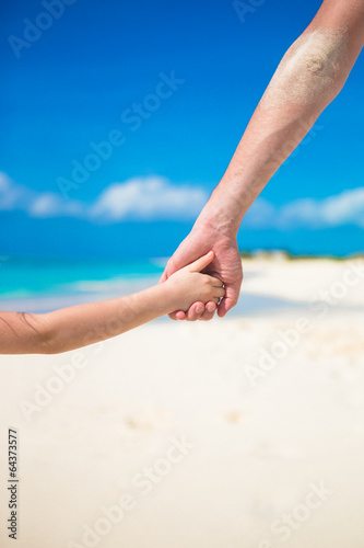 Close up of father and little daughter holding each other hands