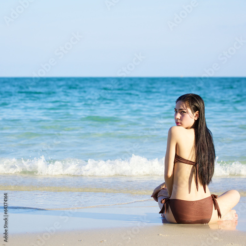beautiful woman in bikini sitting on the beach at summer day