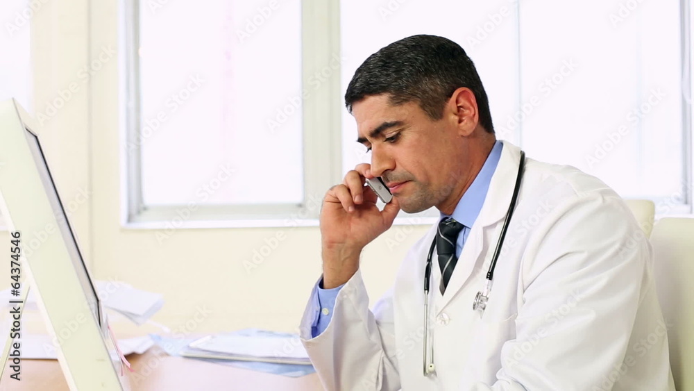 Doctor working at his desk talking on the phone Doctor working at his desk talking on the phone