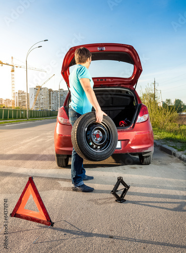 man taking spare wheel out of trunk