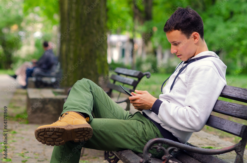 Young man working on pad device in the park Young man working on pad device in the park