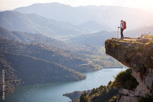 Murais de parede Female hiker standing on cliff and enjoying valley view