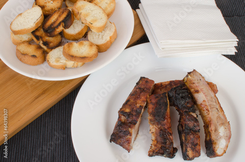 Spareribs on grill with dip and toasted baguette