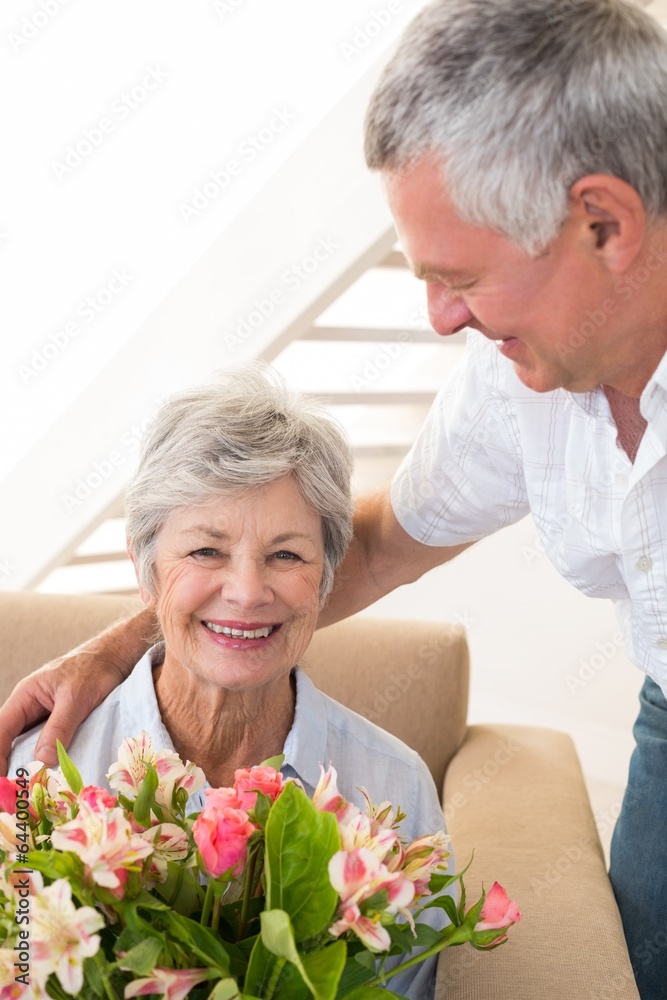 Senior man giving his partner a bouquet of flowers smiling at ca Senior man giving his partner a bouquet of flowers smiling at ca