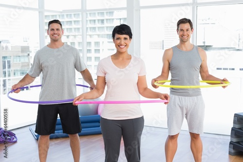 Fitness class holding hula hoops around waist in gym photo