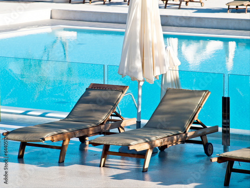 Obraz na plátně Swimming pool and deckchairs