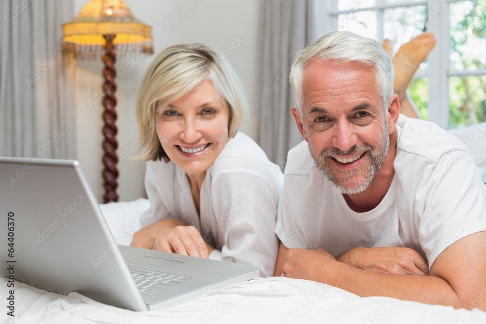 Portrait of a mature couple using laptop in bed Portrait of a mature couple using laptop in bed