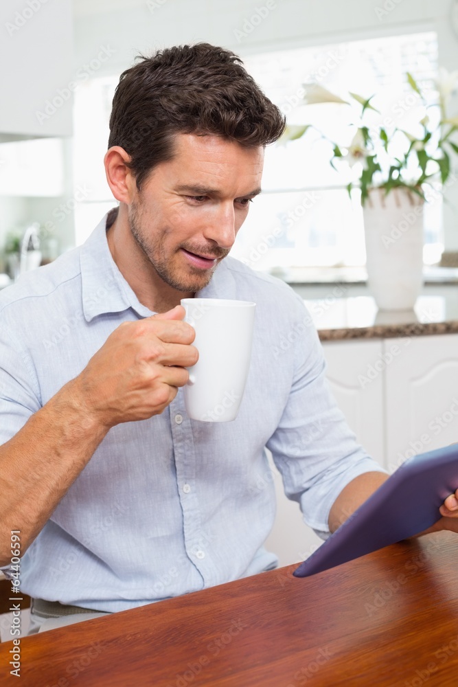 Man using digital tablet while having coffee at home