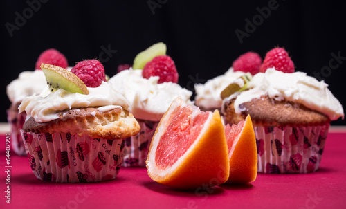 cupcakes with fresh fruits on the red and black background
