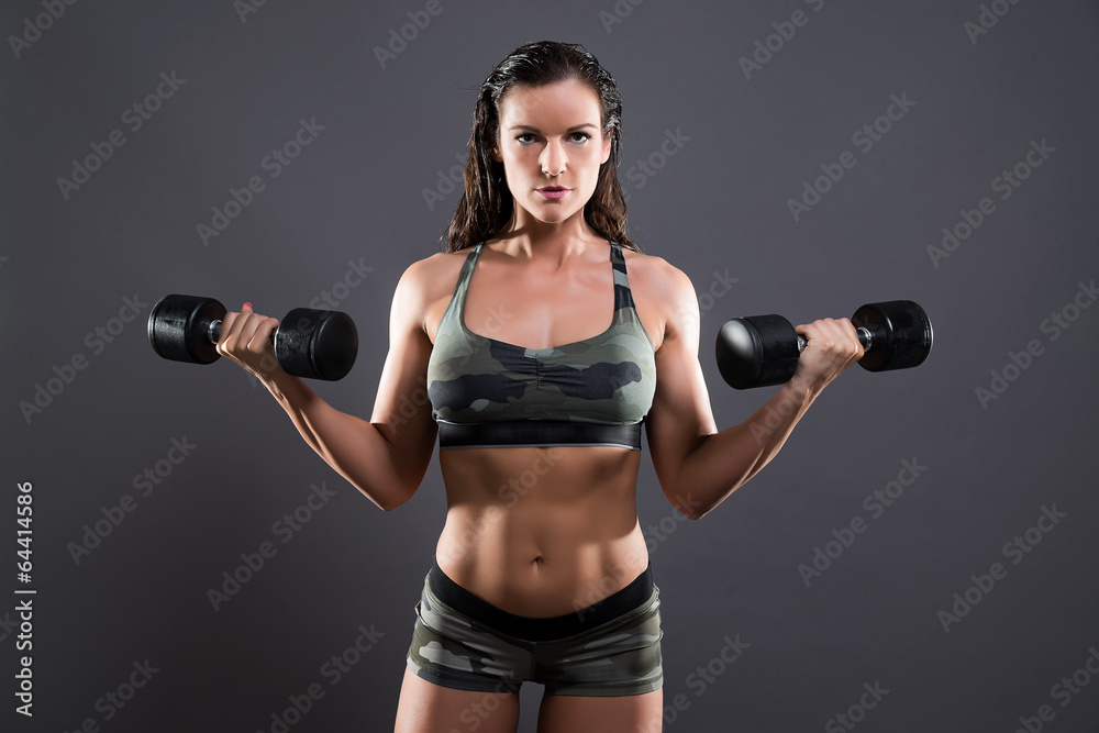 Fitness woman weight lifting with dumbbells. Wearing camouflage