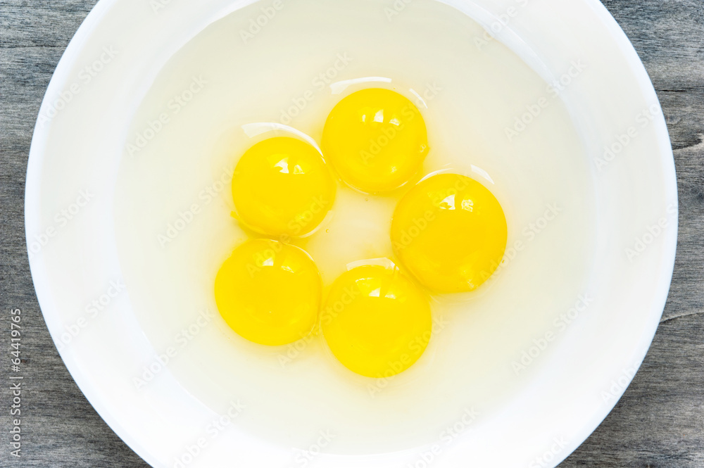 Quail eggs yellow yolk in white porcelain bowl. Closeup. Quail eggs yellow yolk in white porcelain bowl. Closeup.