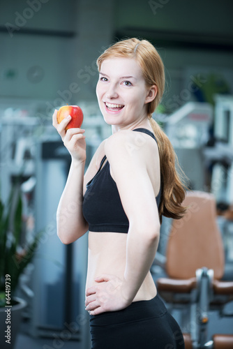 junge Frau mit Apfel im Fitnessstudio
