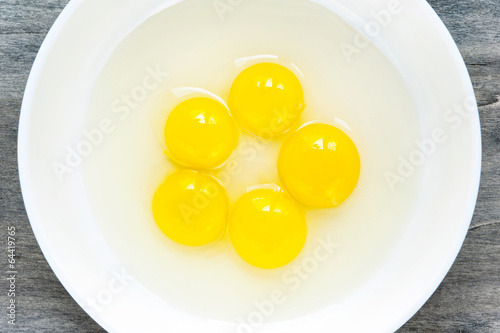 Quail eggs yellow yolk in white porcelain bowl. Closeup.