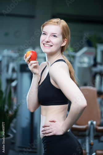 junge Frau mit Apfel im Fitnessstudio