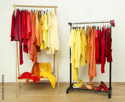 Color coordinated yellow, orange, red clothes hanging on a rack.