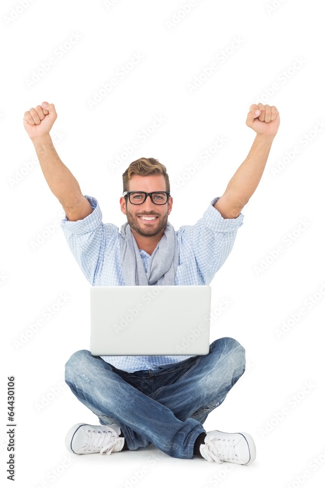Handsome young man cheering at camera with laptop sitting on flo Handsome young man cheering at camera with laptop sitting on flo